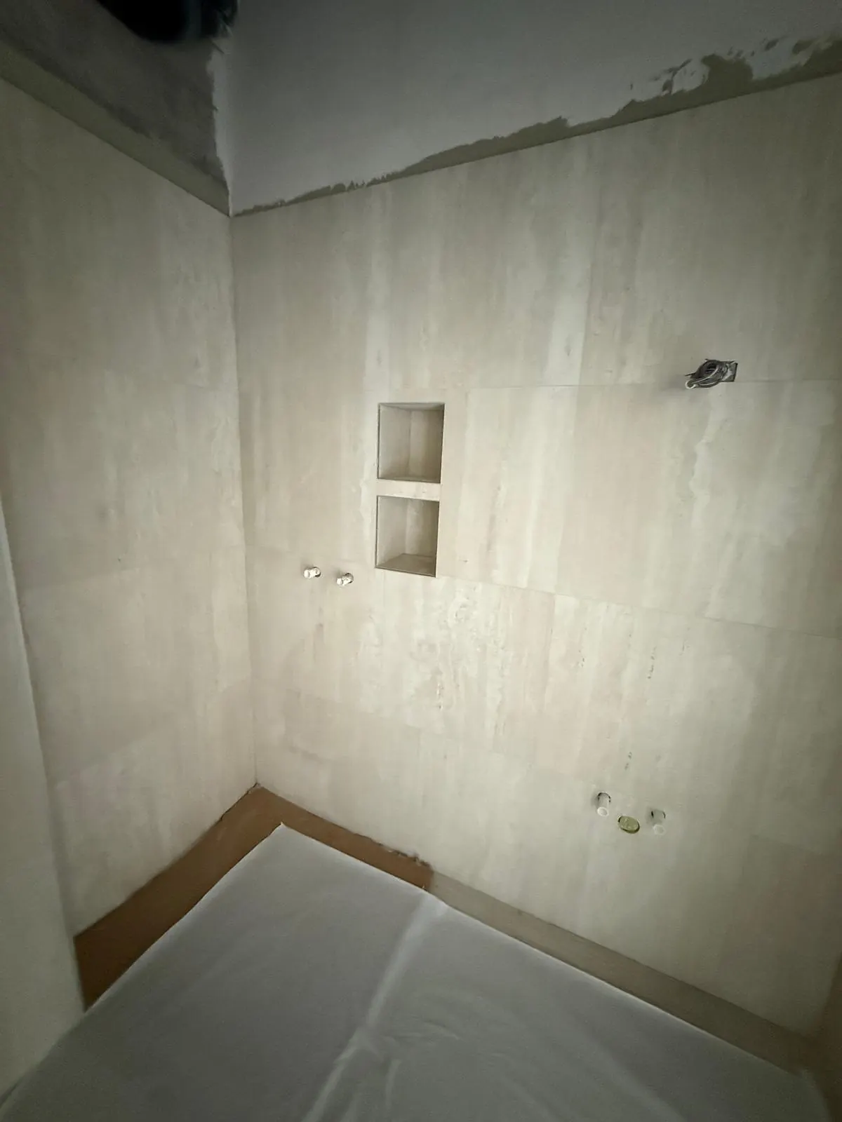 Mur de douche carrelé avec deux niches, sol protégé pendant le chantier