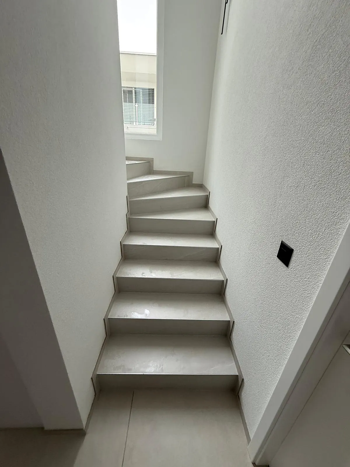 Escalier tournant habillé de carrelage gris clair