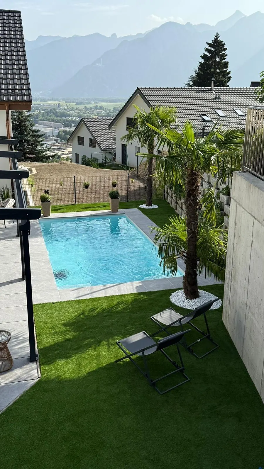 Piscine et terrasse carrelée dans un jardin avec vue sur les montagnes
