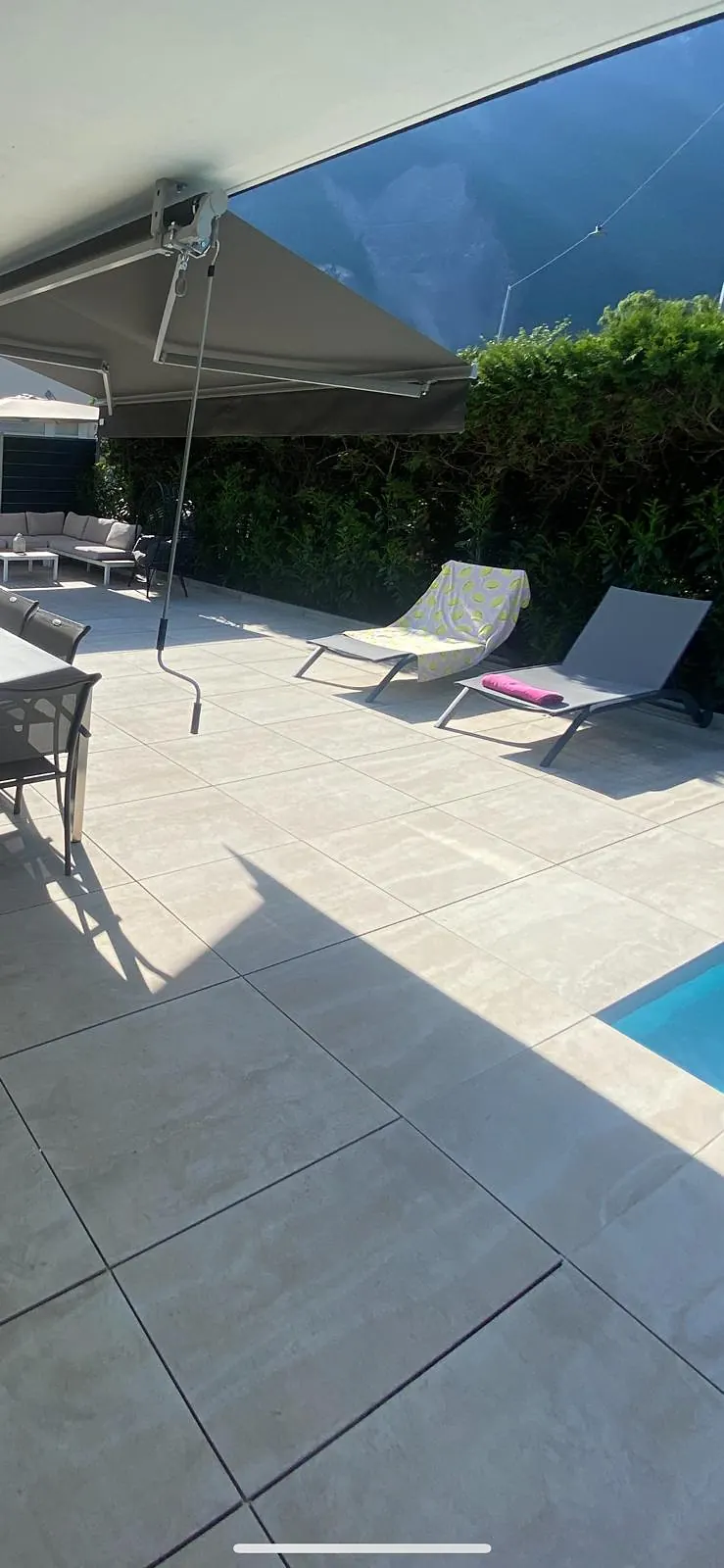 Plage de piscine en dalles grises sous une pergola
