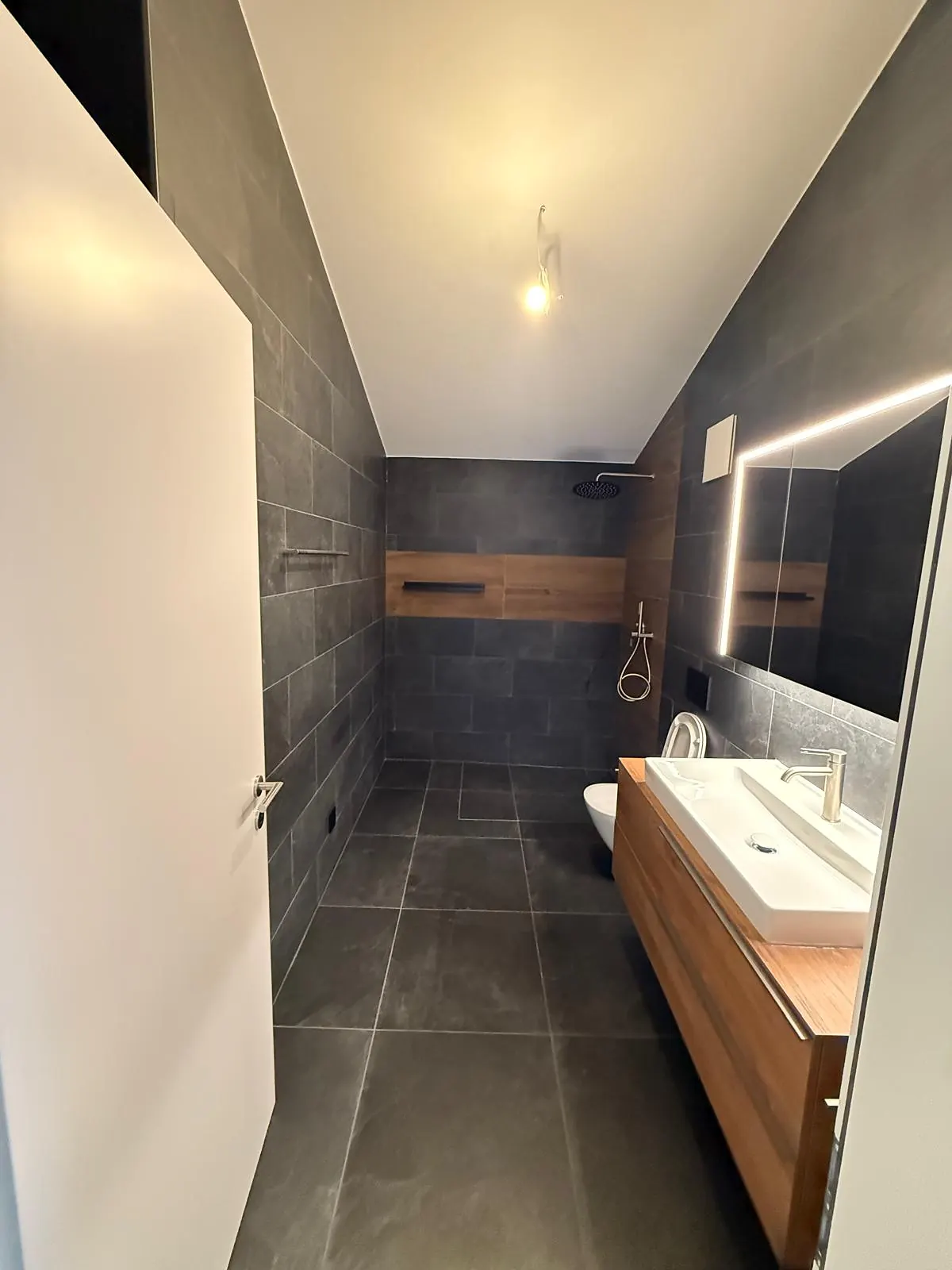 Salle de bain anthracite avec niche murale habillée de bois et miroir lumineux