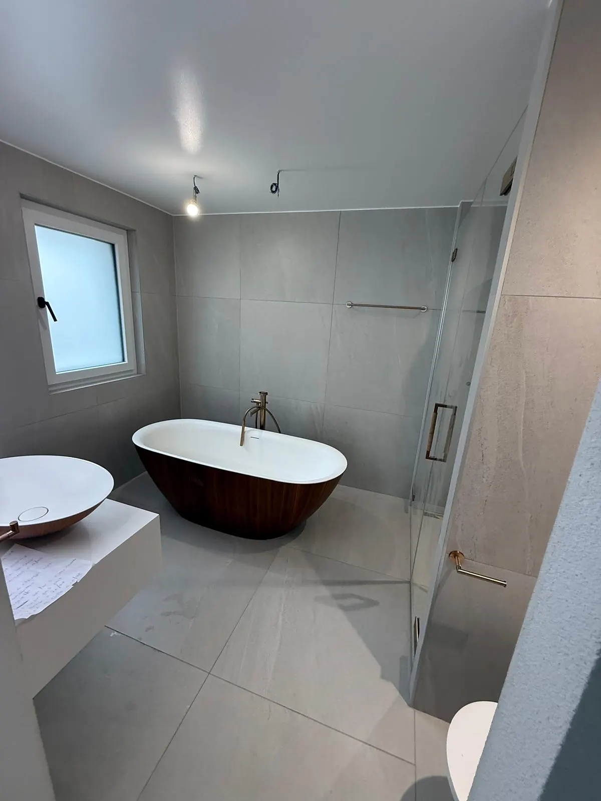 Salle de bain avec baignoire îlot, grands carreaux gris clair au sol et aux murs