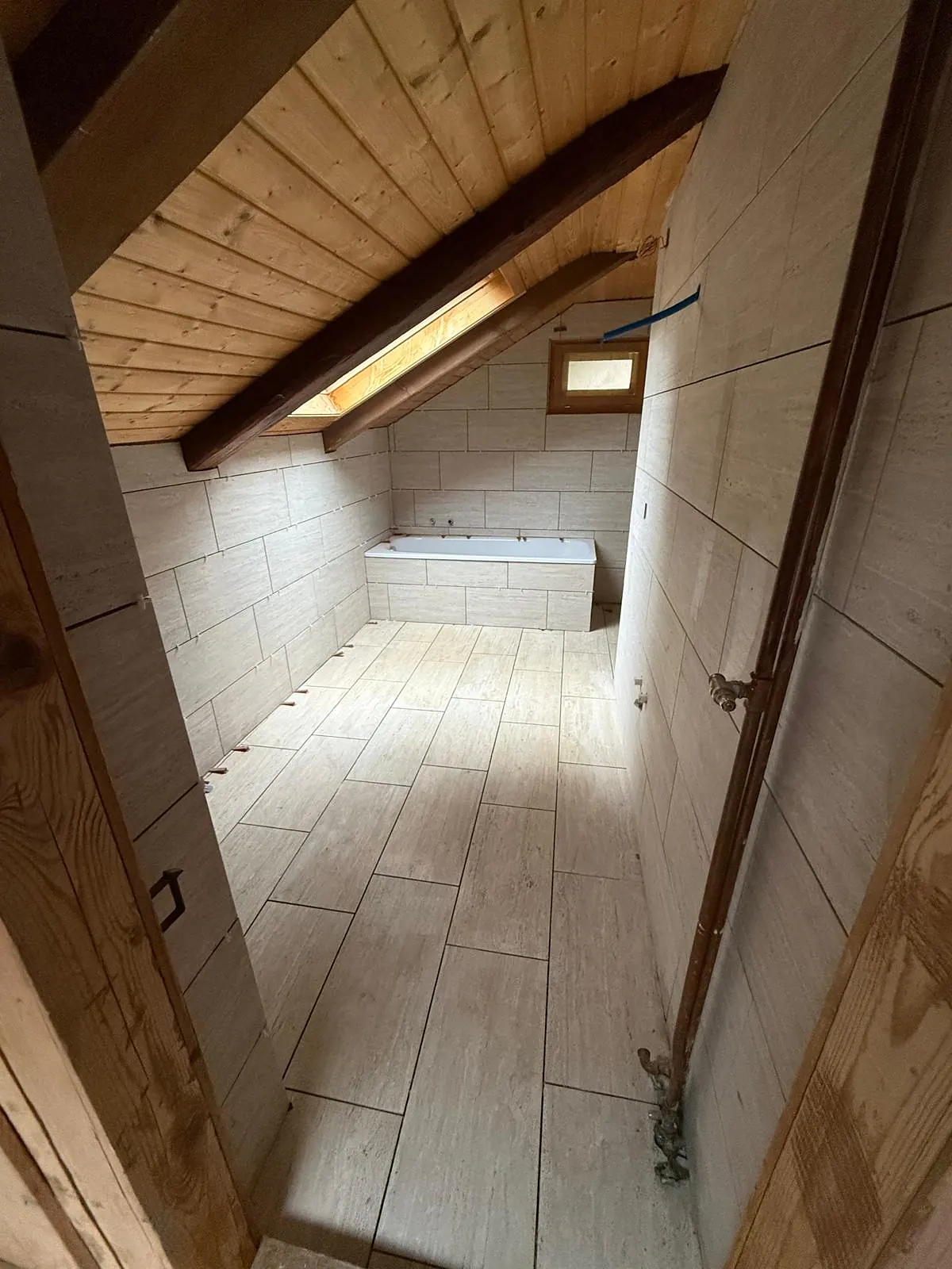 Salle de bain sous les combles, carrelage aspect bois au sol et carreaux clairs aux murs