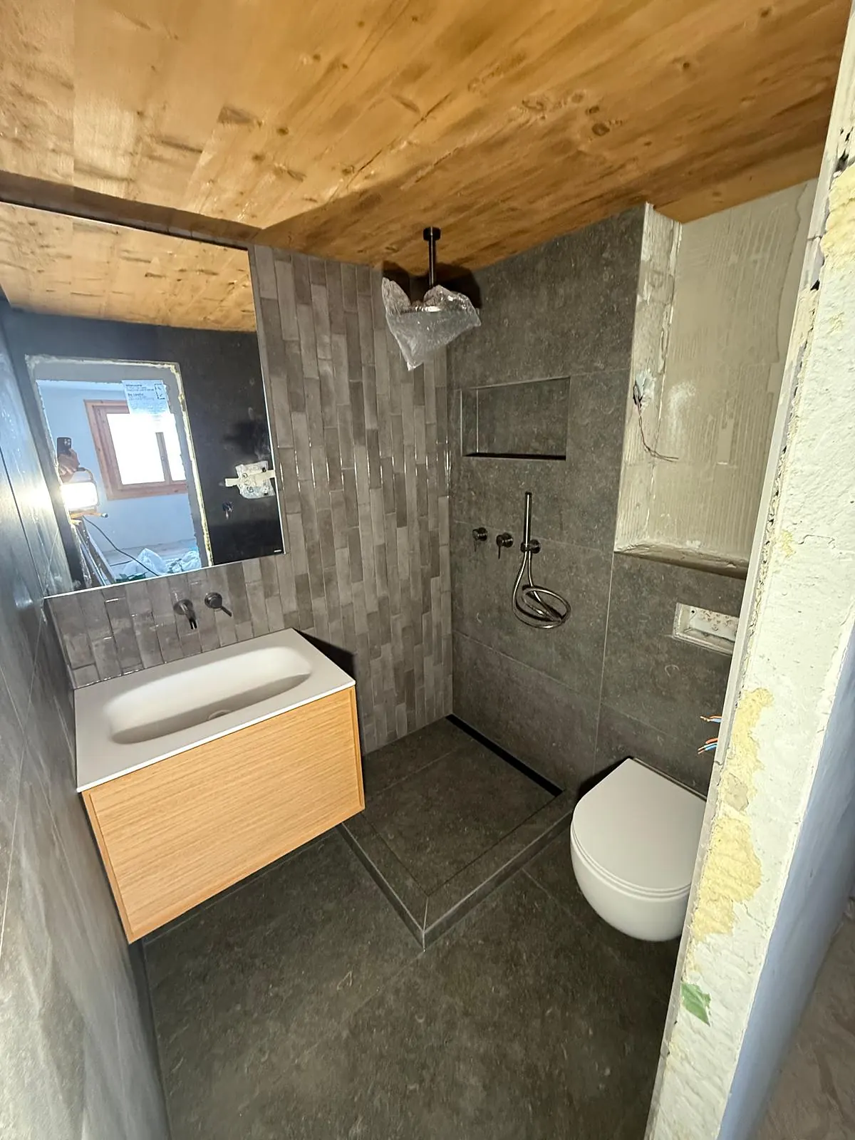 Salle de bain avec douche à l'italienne, carrelage gris et plafond en bois