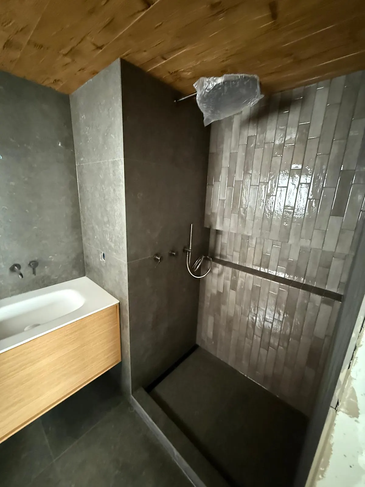 Douche à l'italienne avec carreaux allongés brillants posés à la verticale et sol anthracite